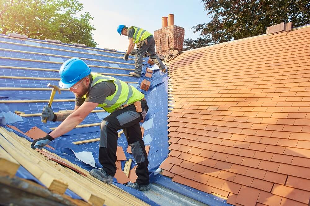 Builders installing shingles on a roof