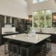 Modern, monochrome kitchen with a large island and black cabinetry and appliances