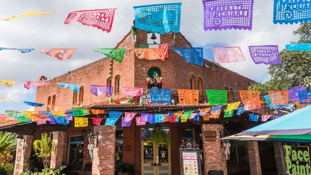 A brick building with colorful banners strung in front of it that read "Market Square"