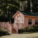 Small pink wooden house with patio in the woods.