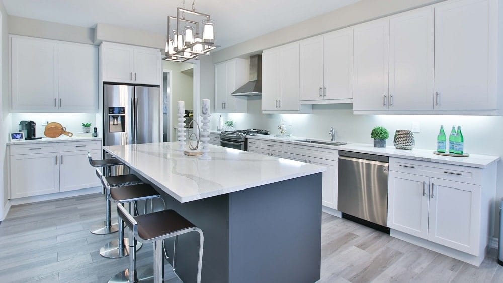 Modern kitchen with large island, white cabinets, and silver appliances.
