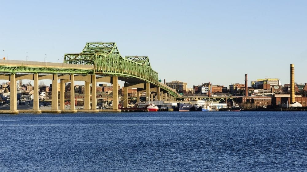A modern bridge spanning a river, looking across the river to the city.
