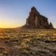 The sun setting behind Shiprock, a rock sculpture in New Mexico.