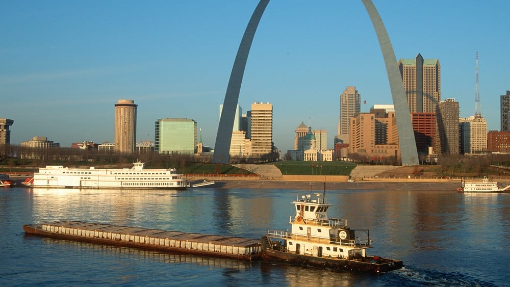 Tugboat pushing barge in front of St. Louis skyline in Missouri.