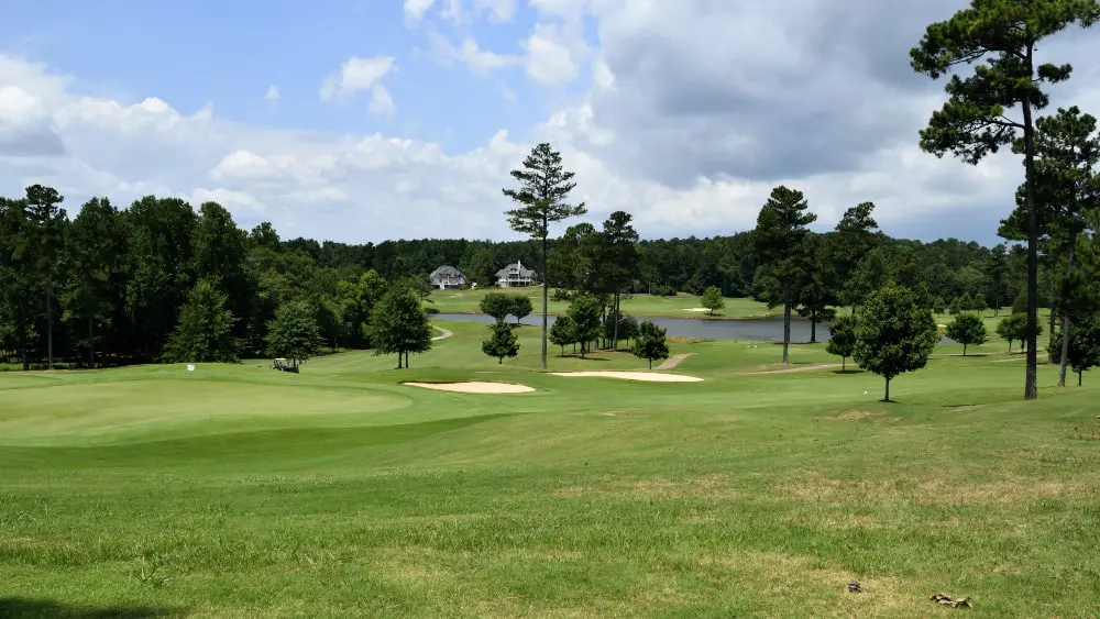 View of golf course greens and sand traps with homes in background