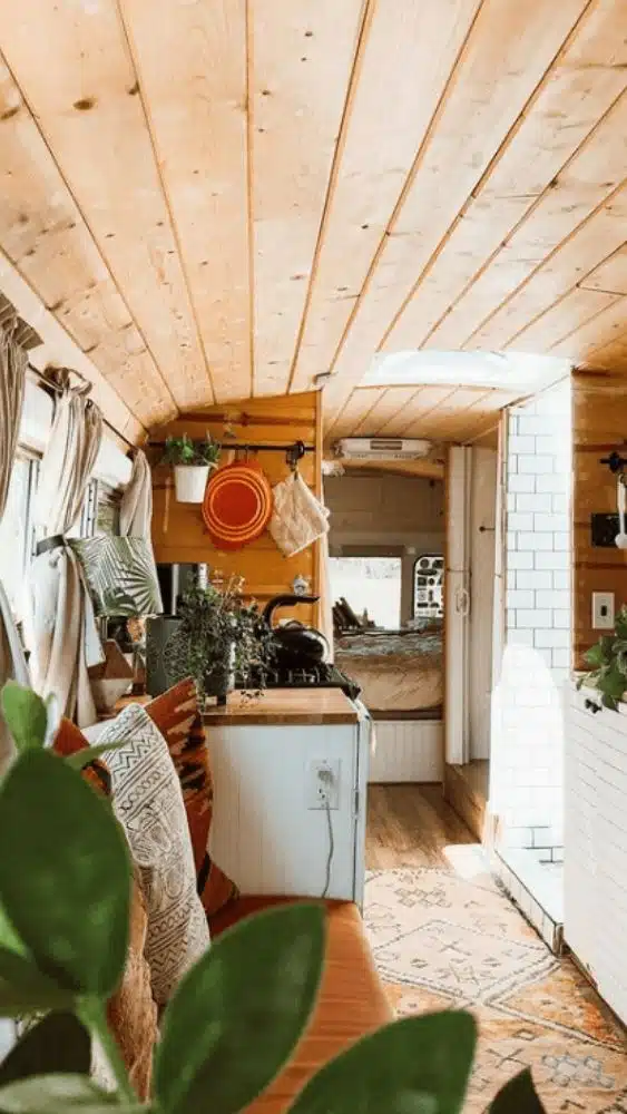 Tiny house with wood accents and white walls, and lots of plants and greenery.