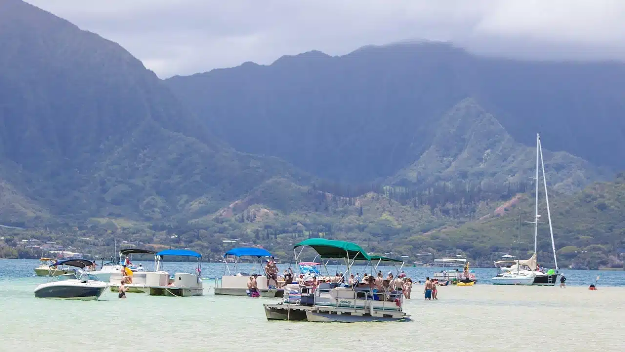 Kaneohe beach on Oahu, Hawaii with mountains in background and boats and people in foreground